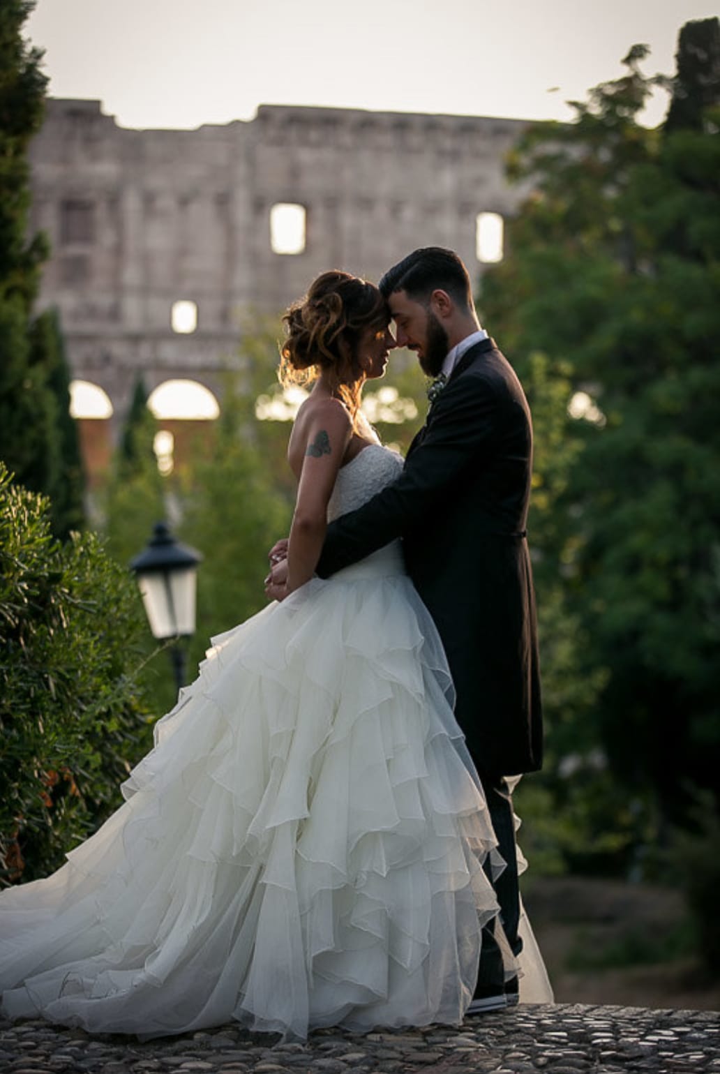Marco and Alessia embracing in front of the Colosseum at sunset